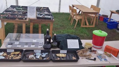 Figure 3: Finds and replicas on display with recently processed finds in trays at back (Image Copyright: Emily Rayner)